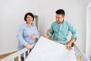 eltern legen eine neu gekaufte matratze in das babybett