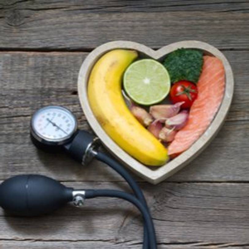 Gemüse, Obst und Lachs in einer Schale, die mit einem Blutdruckmessgerät verbunden ist