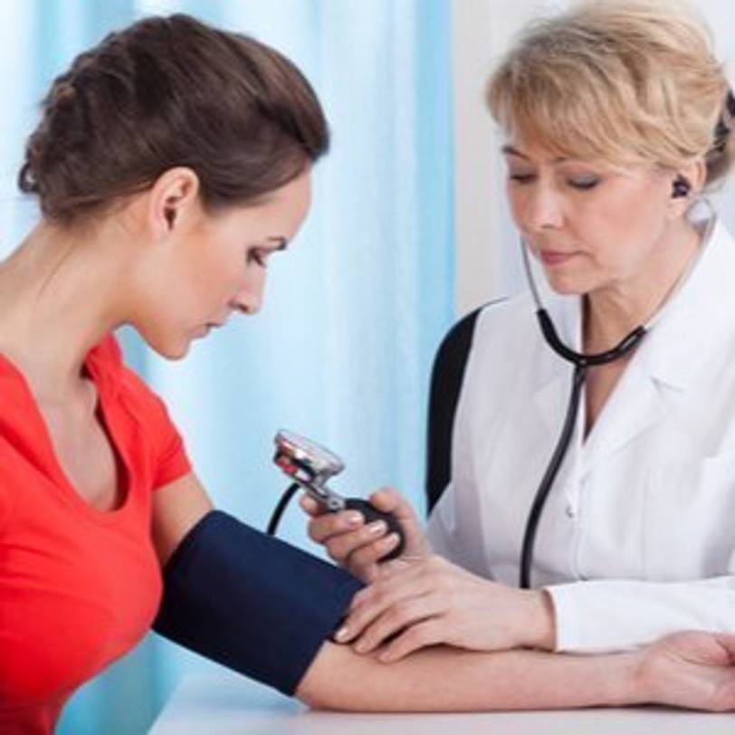 Ärztin, die Blutdruck einer Patientin mit Blutdruckmessgerät überprüft