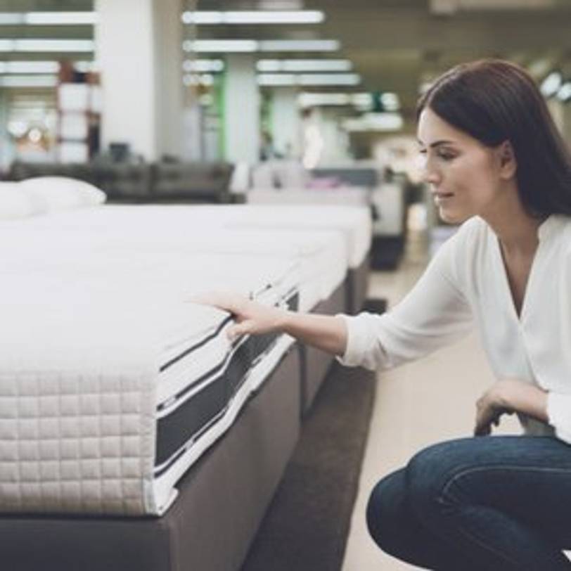 Frau, die sich Boxspringbett in Studio aussucht