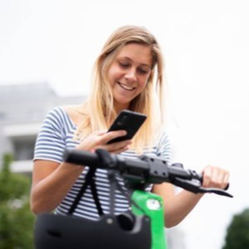 frau meldet sich ueber smartphone fuer e-scooter an
