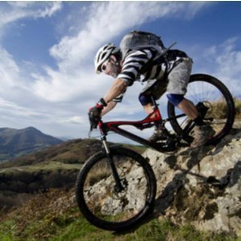 Fahrer, der auf Mountainbike Berg hinab fährt