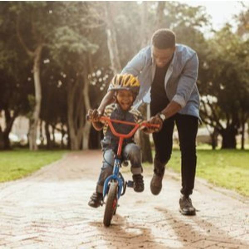 Vater, der mit seinem Kind Fahrrad-Fahren lernt