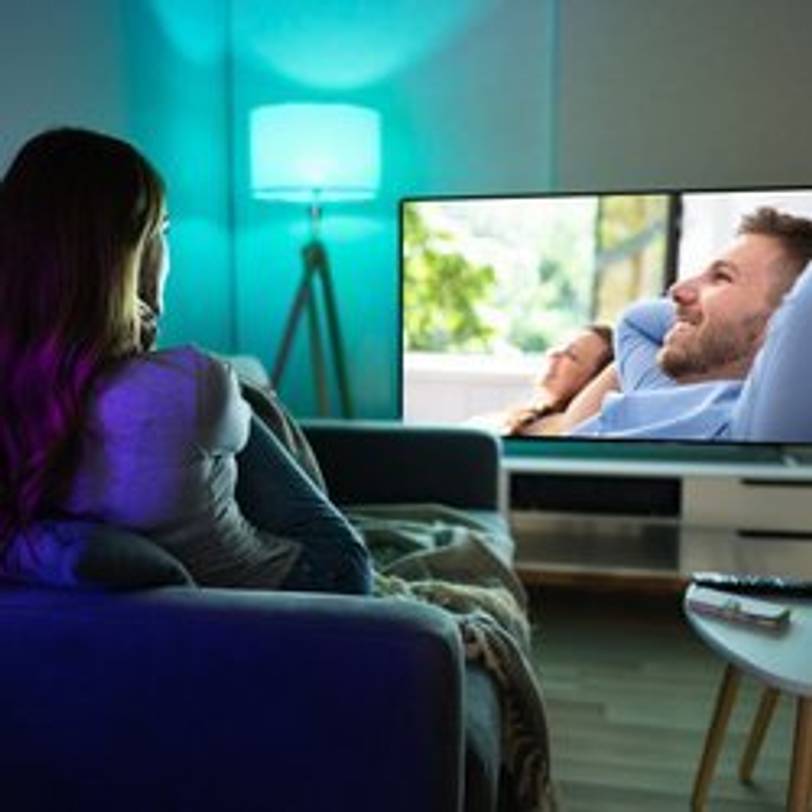 frau sitzt auf dem Sofa und schaut fernsehen