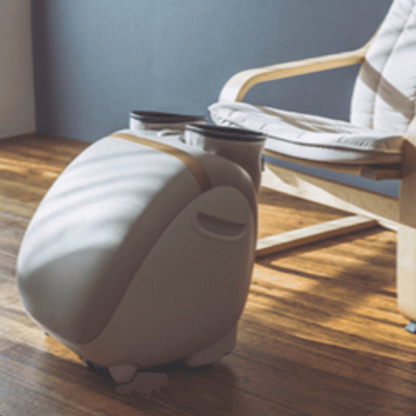 Fußmassagegerät mit Wadenmanschetten vor einem Stuhl