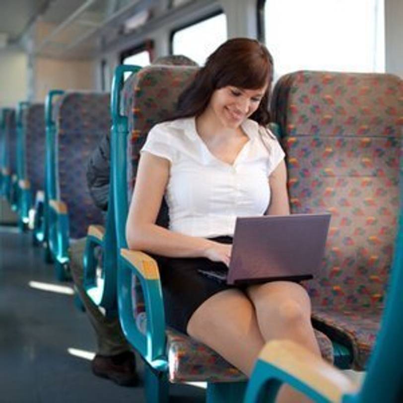 junge Frau, die mit Gaming-Laptop in Zug sitzt