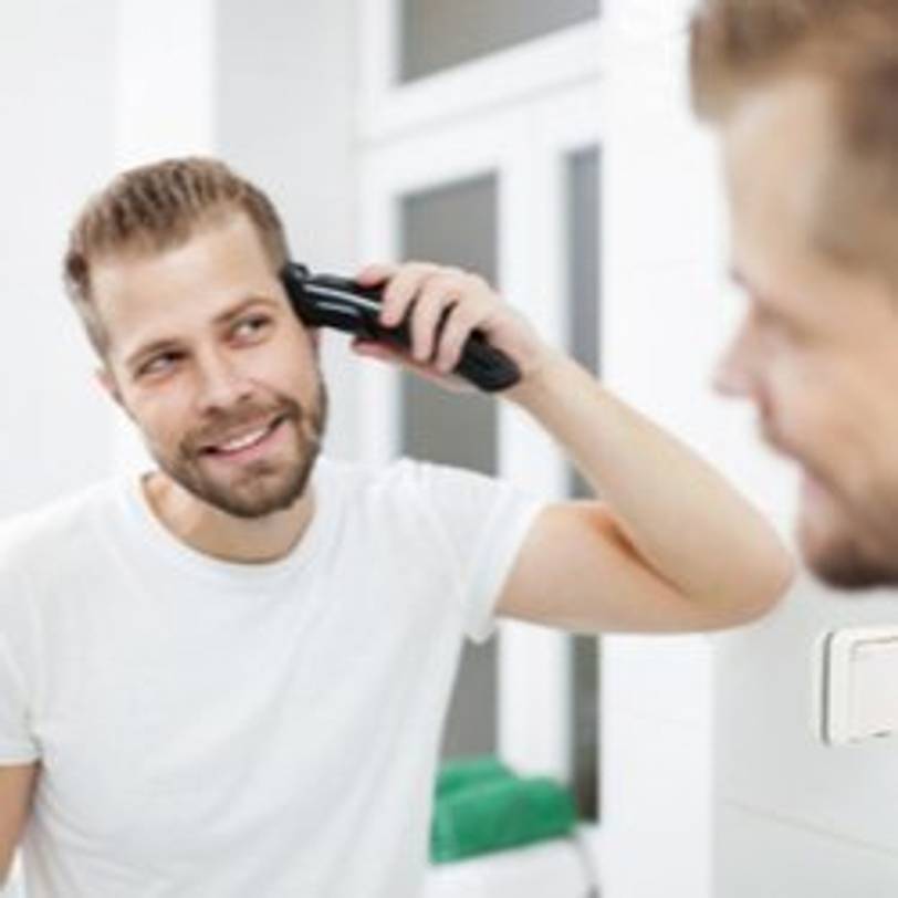 mann vor spiegel benutzt haarschneider