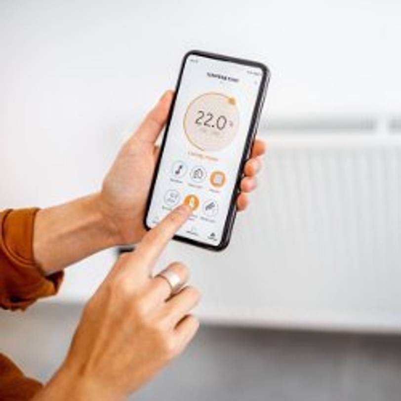 frau bedient heizkoerperthermostat ueber app