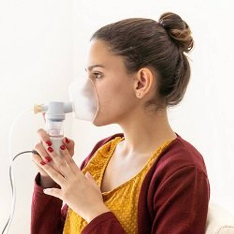 Frau, die mit einem Inhalator Kochsalzlösung inhaliert