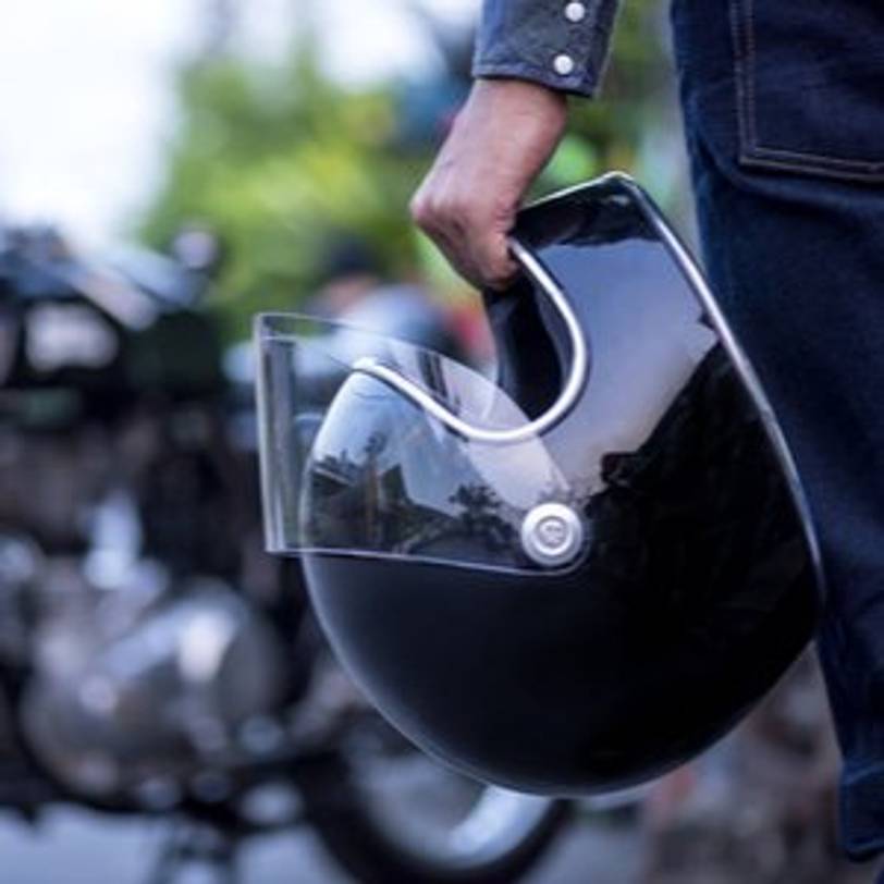 mann haelt schwarzen motorradhelm in der hand