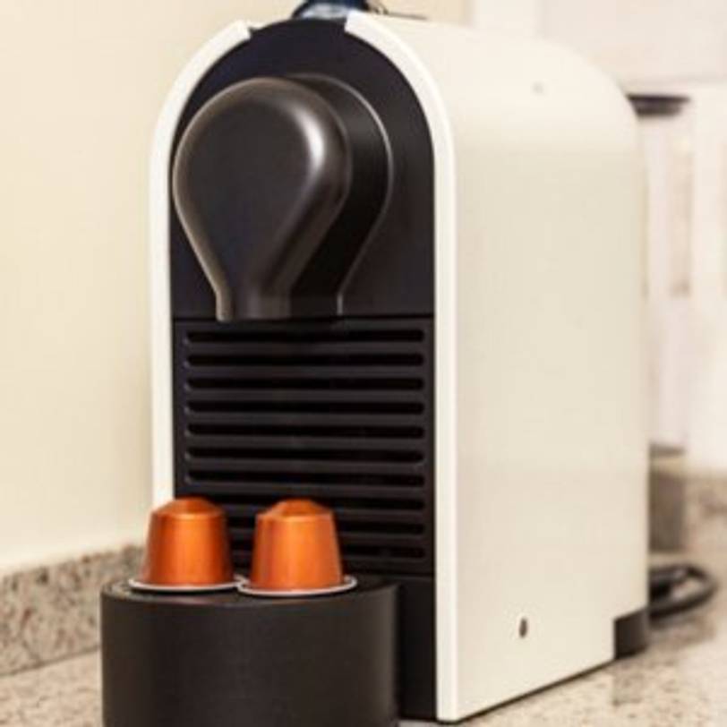 kleine Nespresso-Maschine auf Küchentheke mit zwei Kapseln