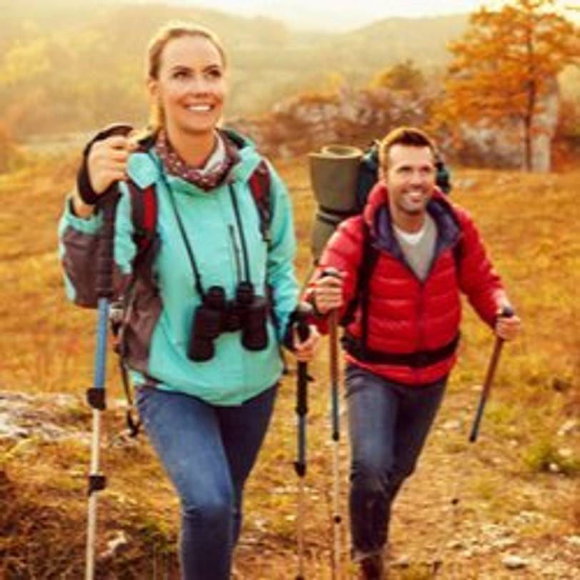 junges Paar, das mit Nordic-Walking-Stöcken unterwegs ist