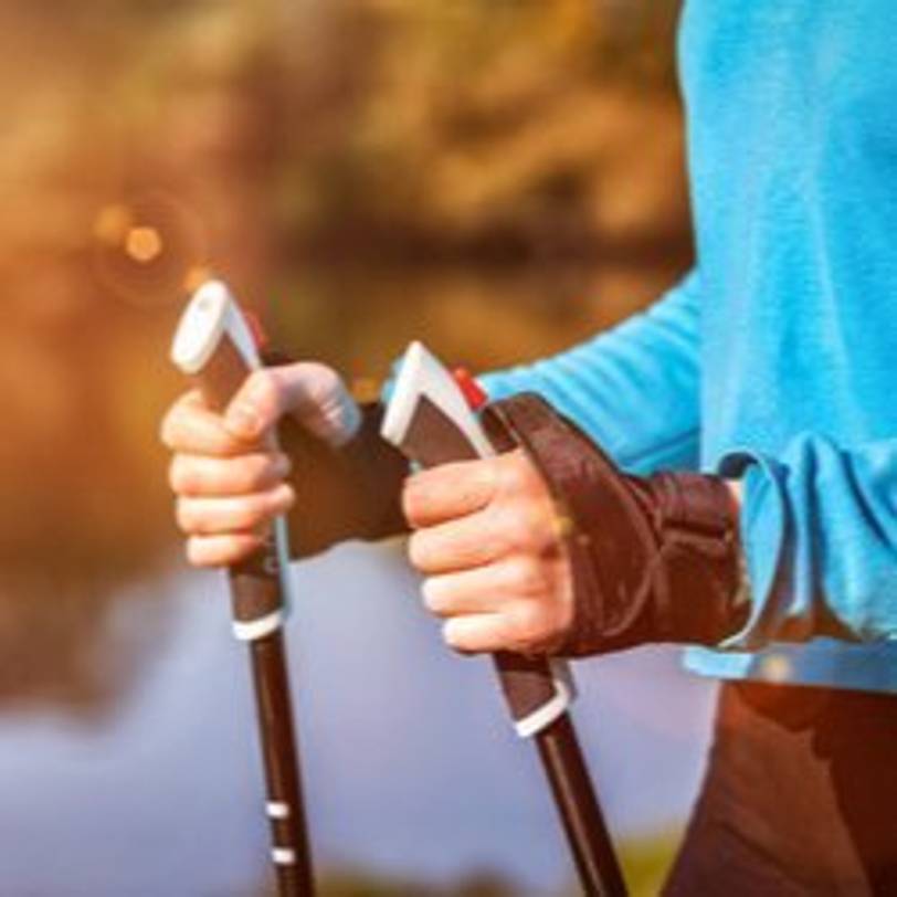 Frau, die sich an Griffen ihrer Nordic-Walking-Stöcke festhält