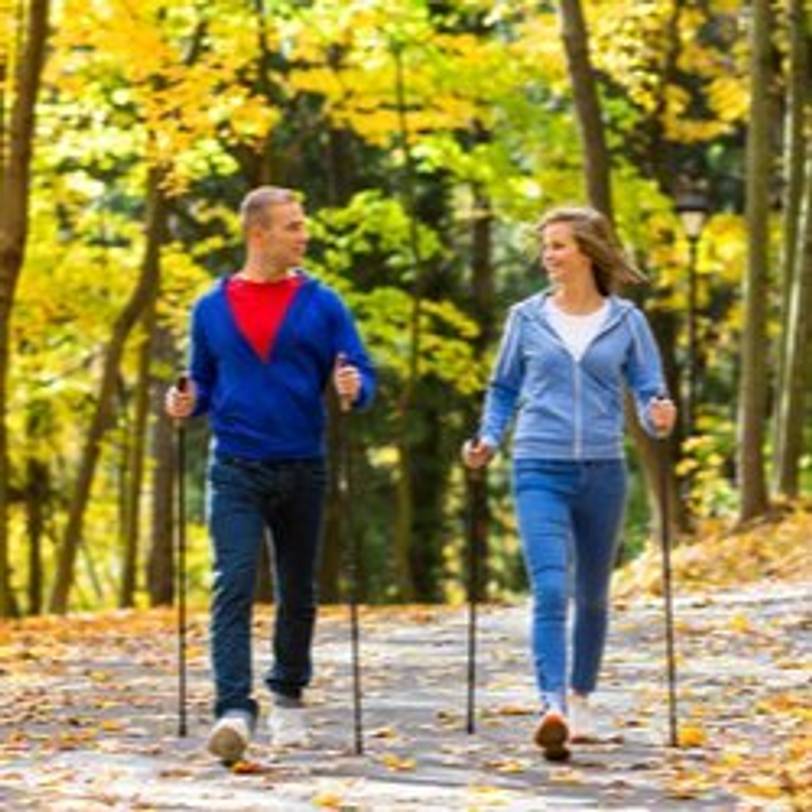 Paar, das mit Nordic-Walking-Stöcken durch einen Park walkt