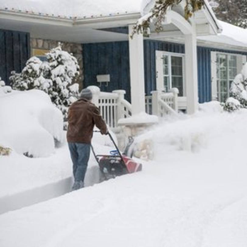 mann macht mit schneefraese weg zum haus frei