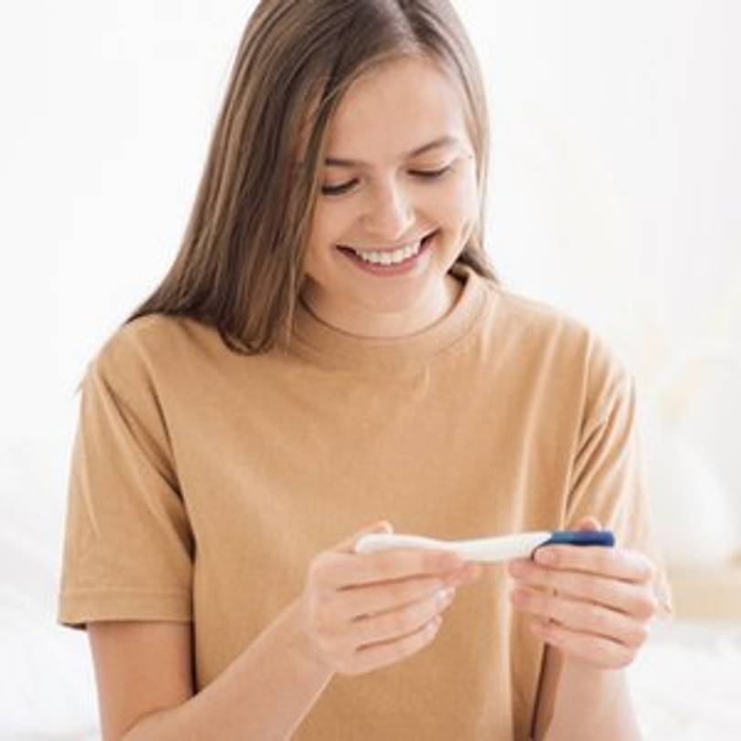 frau freut sich ueber schwangerschaftstest