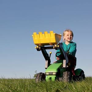 Kind auf Trettraktor auf Wiese