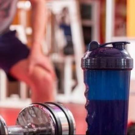 Mann trainiert mit Handel und Shake im Vordergrund.